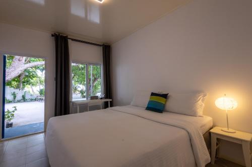 a bedroom with a bed and a large window at LVIS blancura Hotel in Dharavandhoo