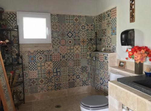 a bathroom with a toilet and a window and tiles at Charmant Appartement au calme avec piscine au pied du Ventoux en Provence in Carpentras