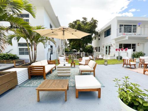 eine Terrasse mit Stühlen, Tischen und einem Sonnenschirm in der Unterkunft Aqua Hotel in Fort Lauderdale