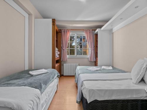 1 dormitorio con 2 camas y ventana en Araucárias 302, en Gramado