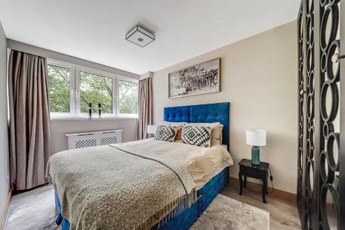 um quarto com uma cama azul e uma janela em My Oasis em Londres