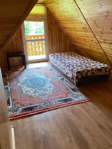 a attic room with a bed and a rug at Domek w lesie in Czerce