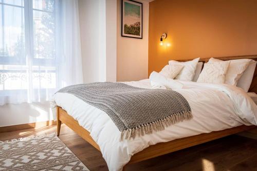 una camera da letto con un grande letto bianco con una finestra di L'Albatros 006 - Hypercentre * Cosy * Wifi a Saint-Quentin