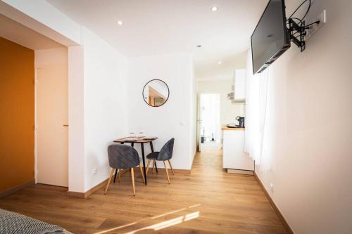 un salon avec une table, des chaises et une télévision dans l'établissement L'Albatros 006 - Hypercentre * Cosy * Wifi, à Saint-Quentin