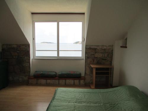 1 dormitorio con ventana, cama y mesa en Apartments Acalinović, en Vis