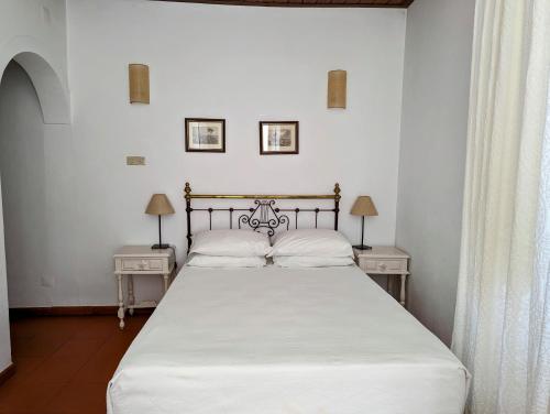 a bed in a bedroom with two tables and two lamps at Hotel Solar de Monfalim in Évora
