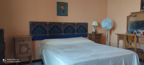 a bedroom with a bed and a table with a fan at Casa vacanze nel cuore della sicilia in Santa Caterina Villarmosa