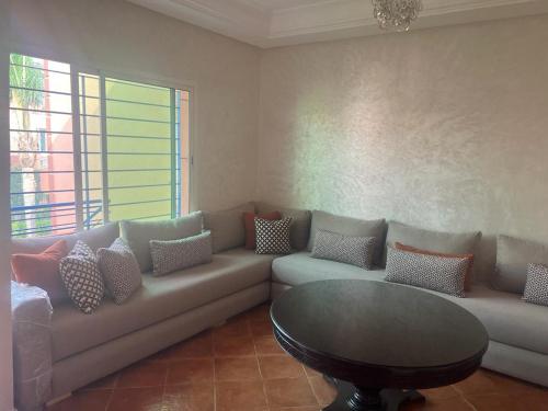 a living room with a couch and a table at Superbe appartement avec piscine en bord de mer in Douar Ourlali