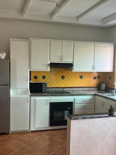 a kitchen with white cabinets and a refrigerator at Superbe appartement avec piscine en bord de mer in Douar Ourlali