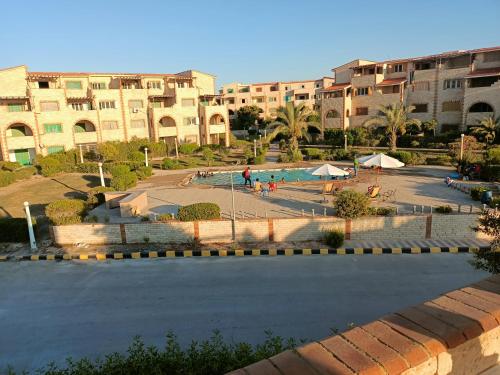 a courtyard with a swimming pool in front of a building at شاليه في قرية هيلو بيتش في الكيلو ٥٠ in Borg El Arab