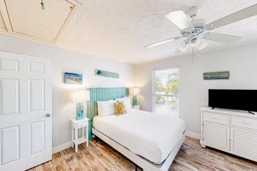a white bedroom with a bed and a ceiling fan at Breezy Keys in Key Colony Beach