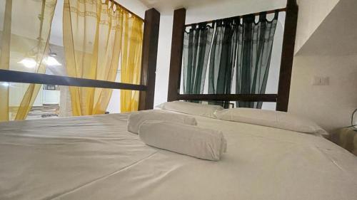 Una cama blanca con almohadas blancas encima. en via ROMA 100 ROOMS, en Enna
