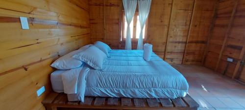 a bed in a wooden room with a window at Cabaña 1 santo cielo in Villa de Leyva