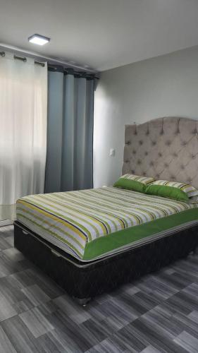 una camera da letto con un grande letto con cuscini verdi di ALQUILER CASA DE PLAYA FRENTE AL MAR / “CONDOMIO CASTILLO DE ARENA”-HUARMEY 