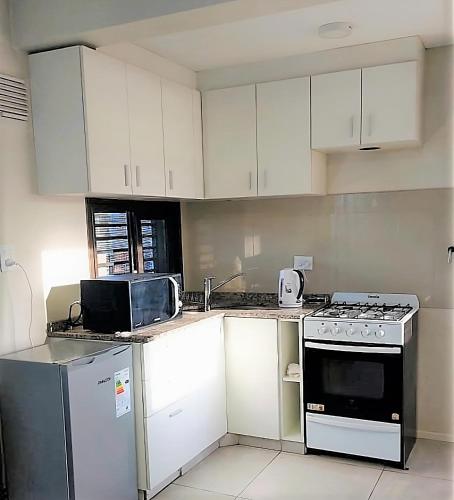 a kitchen with white cabinets and a stove top oven at Departamento Olympia Village - Mendoza in Mendoza