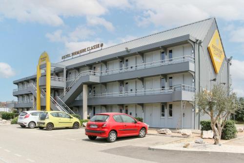 a red car parked in a parking lot in front of a hotel at Première Classe Aéroport Marseille in Vitrolles