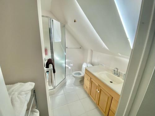 Cozy 1-bedroom loft with falls view 4mins to falls في شلالات نياجارا: حمام أبيض مع حوض ومرحاض