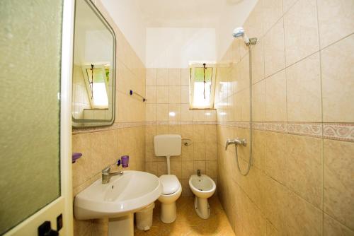 a bathroom with a sink and a toilet and a mirror at Rei’s place in Vlorë