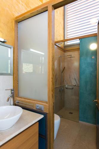 a bathroom with a sink and a glass shower at Eleni's Serenity - Discovering Sapphire Harmonies in Ravdhoúkha