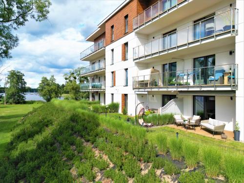 an apartment building with a garden in front of it at Port View plus miejsce w hali garażowej in Iława