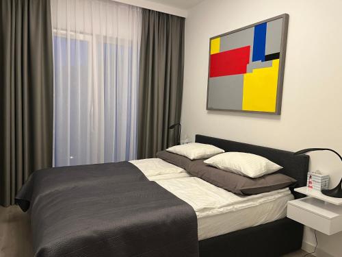 a bedroom with a bed and a painting on the wall at Apartament w Let's Sea Baltic Park in Gąski
