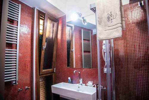 a red tiled bathroom with a sink and a mirror at Casa Blu in Vietri