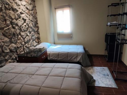 um quarto com duas camas e uma parede de pedra em casa consulado em Ciudad Juárez