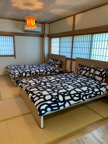 GUEST HOUSE APPLE في أوساكا: سريرين يجلسون في غرفة مع نوافذ
