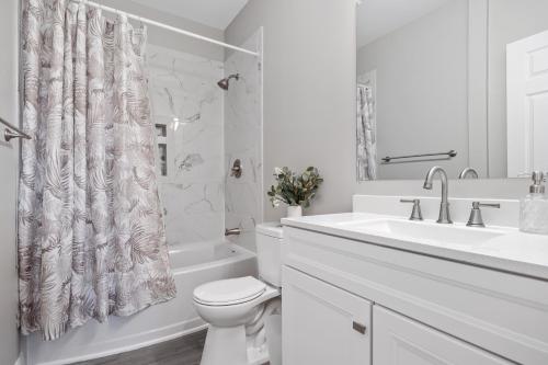 a white bathroom with a toilet and a sink at Beautiful Condo Near Boardwalk Beach & Downtown in Ocean City