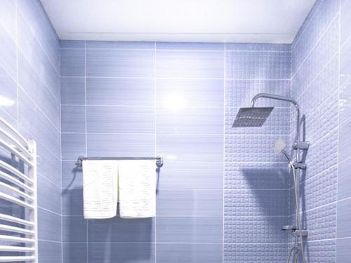 a blue tiled bathroom with a shower with towels at Hotel Caucasus Borjomi in Borjomi