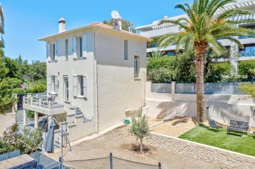 a white house with a palm tree in front of a building at Maison Sara Juan les Pins in Juan-les-Pins