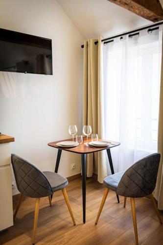 - une table avec des verres à vin et 2 chaises dans la chambre dans l'établissement L'Albatros 004 - Hypercentre * Cosy * Wifi, à Saint-Quentin