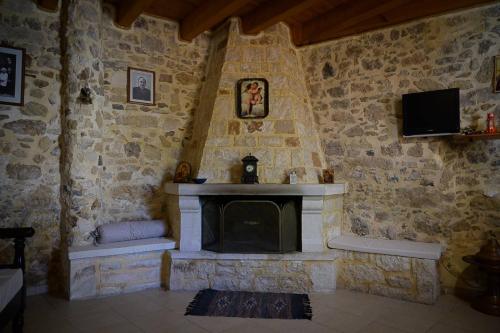 Traditional Stone Mezonete في Krousón: غرفة حجرية بها موقد وتلفزيون