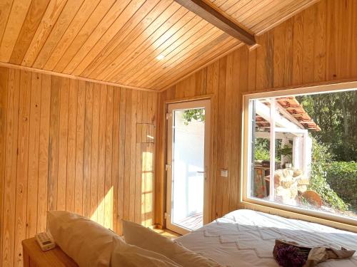 a bedroom with a large window in a wooden wall at Nativo Natureza Pink Wood Cabin in Cela