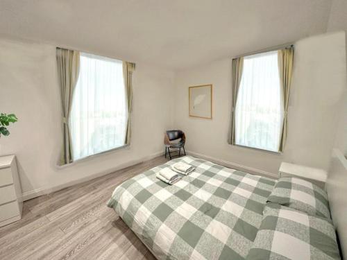 a bedroom with a green and white bed with windows at 2 minutes from Hyde Park, Private Room F in London