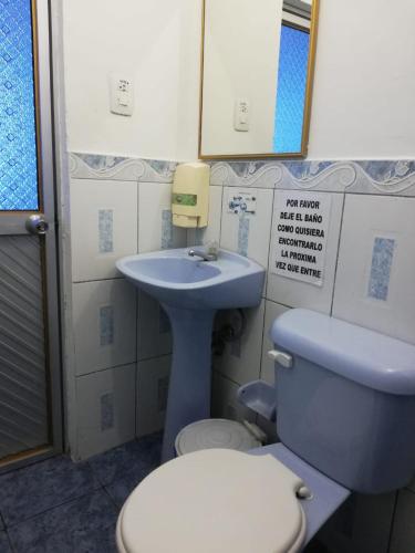 a bathroom with a blue toilet and a sink at Hostal Amazónico Bello Amanecer in Nueva Loja