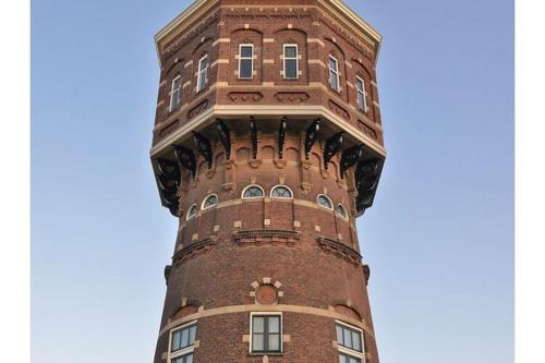 a tall brick tower with windows on top of a building at Renovated luxury water tower within walking distance of the beach boulevard in Vlissingen