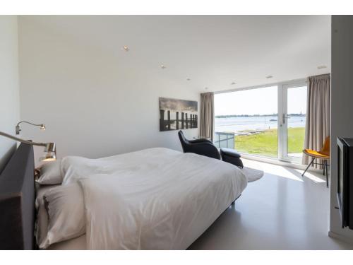 ein weißes Schlafzimmer mit einem Bett und einem Fenster in der Unterkunft Modern Holiday Home in Kamperland near the Sea in Kamperland