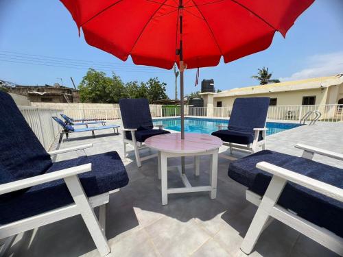 a patio with a table and chairs and a red umbrella at Exclusive Holiday Villa with Pool in Accra in Accra