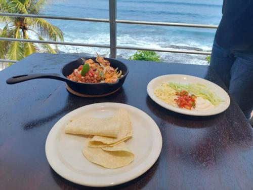 een tafel met twee borden eten en een kom eten bij KaiBlue Hotel y Restaurante in La Libertad