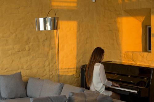 a woman playing a piano in a living room at Eleni's Serenity - Discovering Sapphire Harmonies in Ravdhoúkha