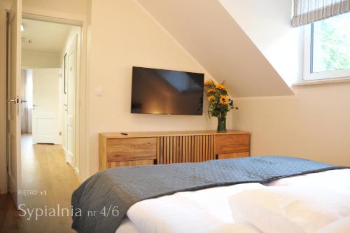 a bedroom with a bed and a tv on a wall at Mazury Haus in Ruciane-Nida