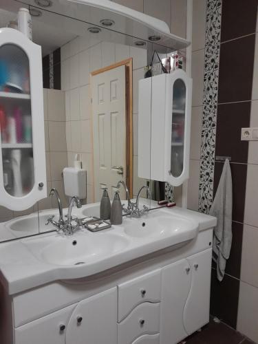 baño con lavabo blanco y 2 espejos en Családi szálláshely a Pilisben, en Piliscsév