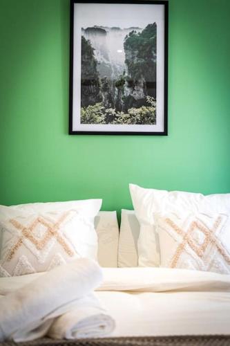 - un lit avec des oreillers blancs et une photo sur le mur dans l'établissement L'Albatros 003- Hypercentre * Cosy * Wifi, à Saint-Quentin