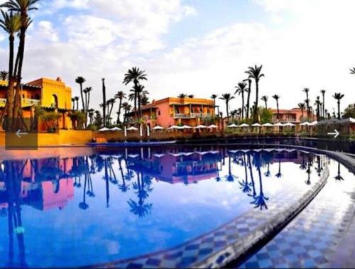een groot zwembad met palmbomen en gebouwen bij Marrakech Palmeraie village in Marrakesh