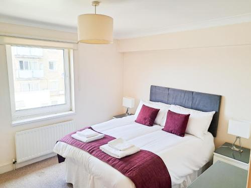 een slaapkamer met een groot wit bed met paarse kussens bij Wimbledon Apartment in Londen