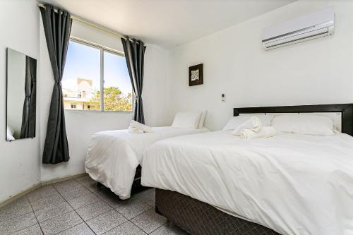 two beds in a room with a window at Apto a 30 metros do mar em Canasvieiras CBE105 in Florianópolis