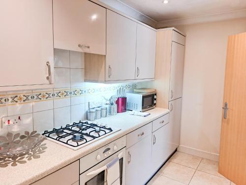 a kitchen with white cabinets and a stove top oven at Wimbledon Apartment in London