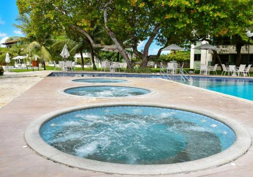 einen Pool mit drei Whirlpools mit Tischen und Stühlen in der Unterkunft Carneiros Beach Resort Flat Térreo 2 quartos in Praia dos Carneiros