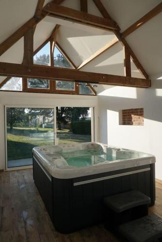 une baignoire jacuzzi dans une chambre avec toit dans l'établissement L'Escapade du Vexin normand - Spa, à Longchamps